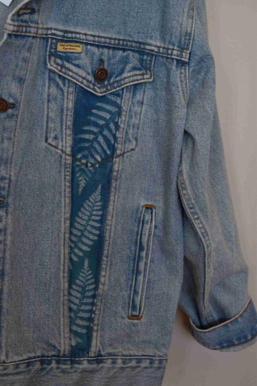 a blue jean jacket with a fern design on it.