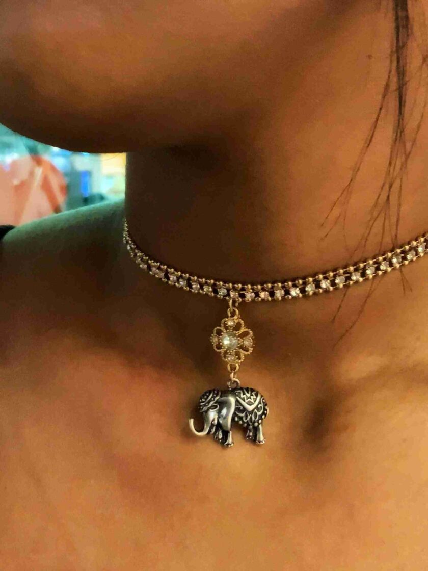 a woman wearing a necklace with an elephant charm.