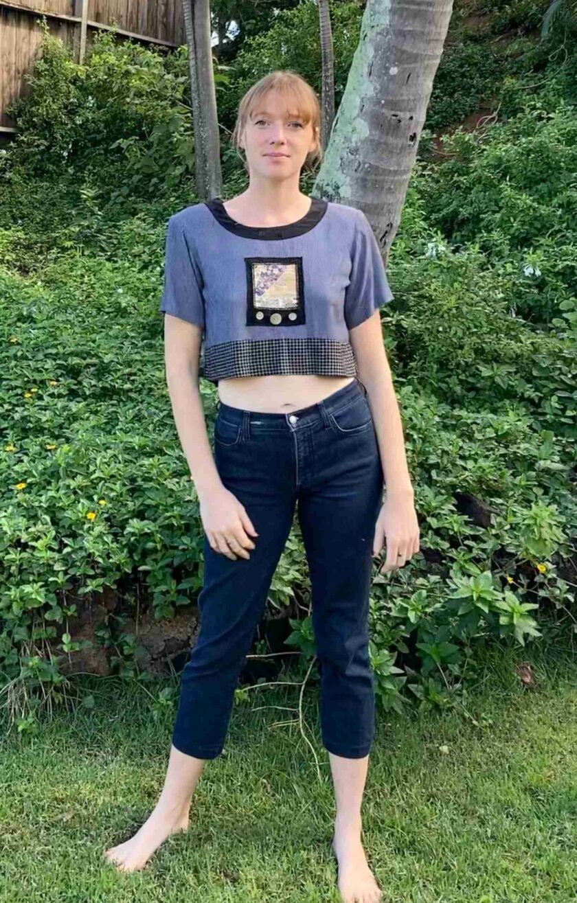a woman standing in the grass wearing a crop top.