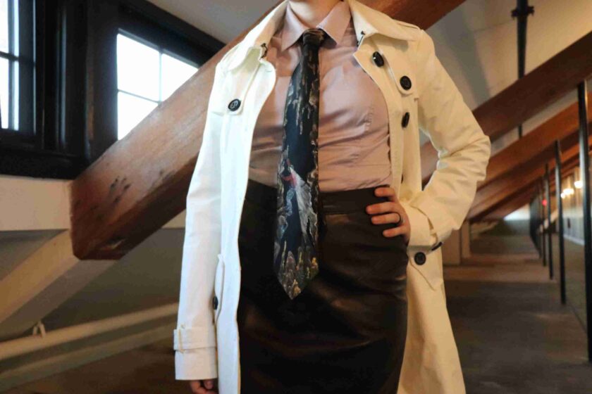 a woman in a skirt and trench coat posing for a picture.