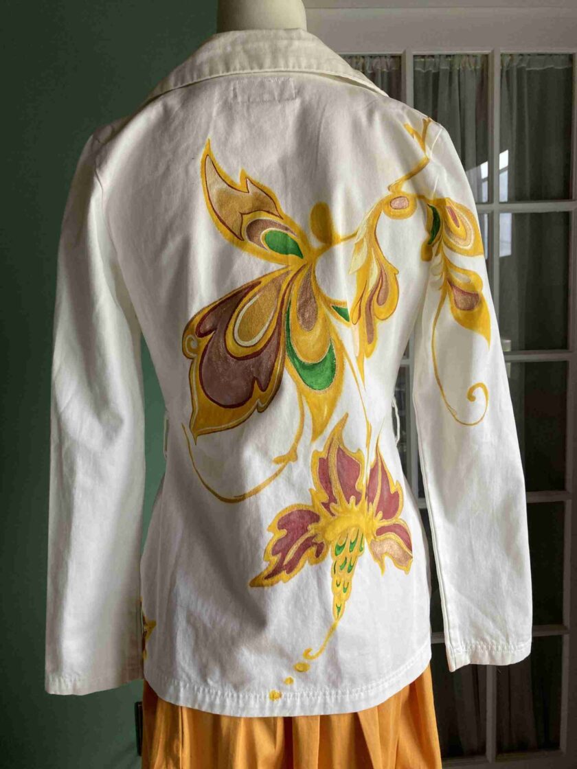 a woman's white jacket with yellow and red flowers on it.