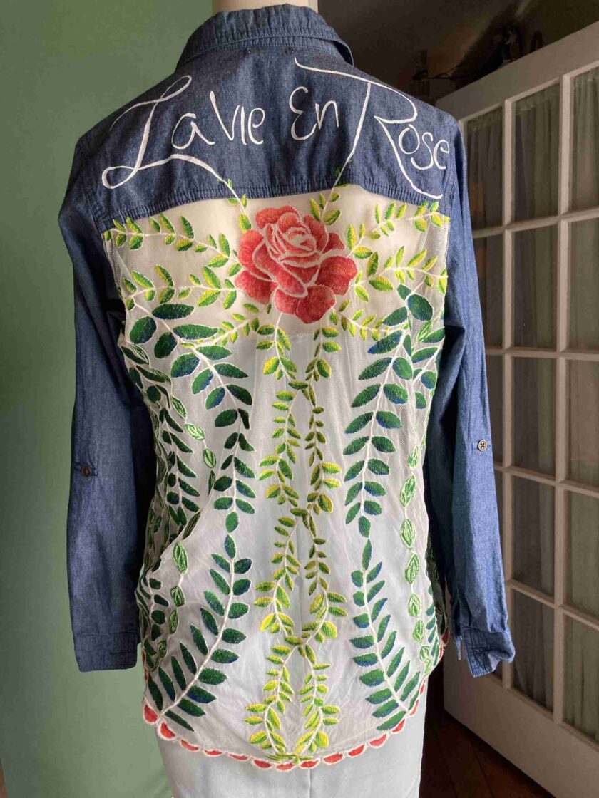 a denim jacket with a rose painted on it.