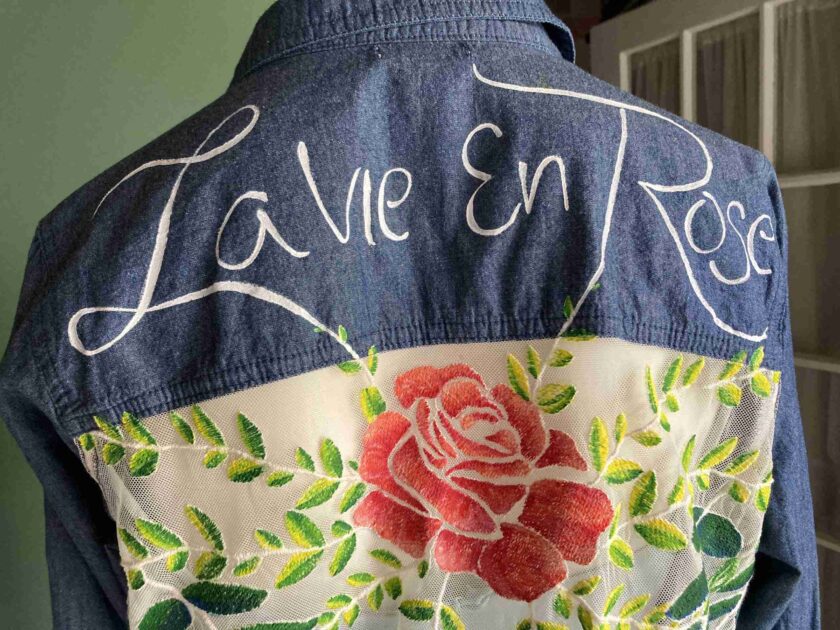 a denim jacket with a rose embroidered on it.