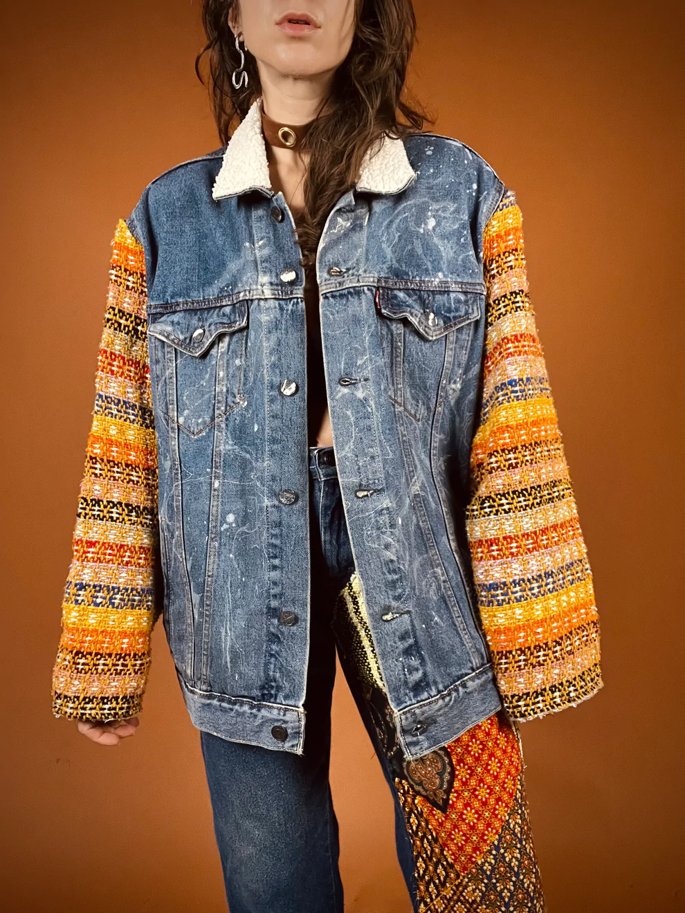 a woman wearing a jean jacket with a colorful sleeve.