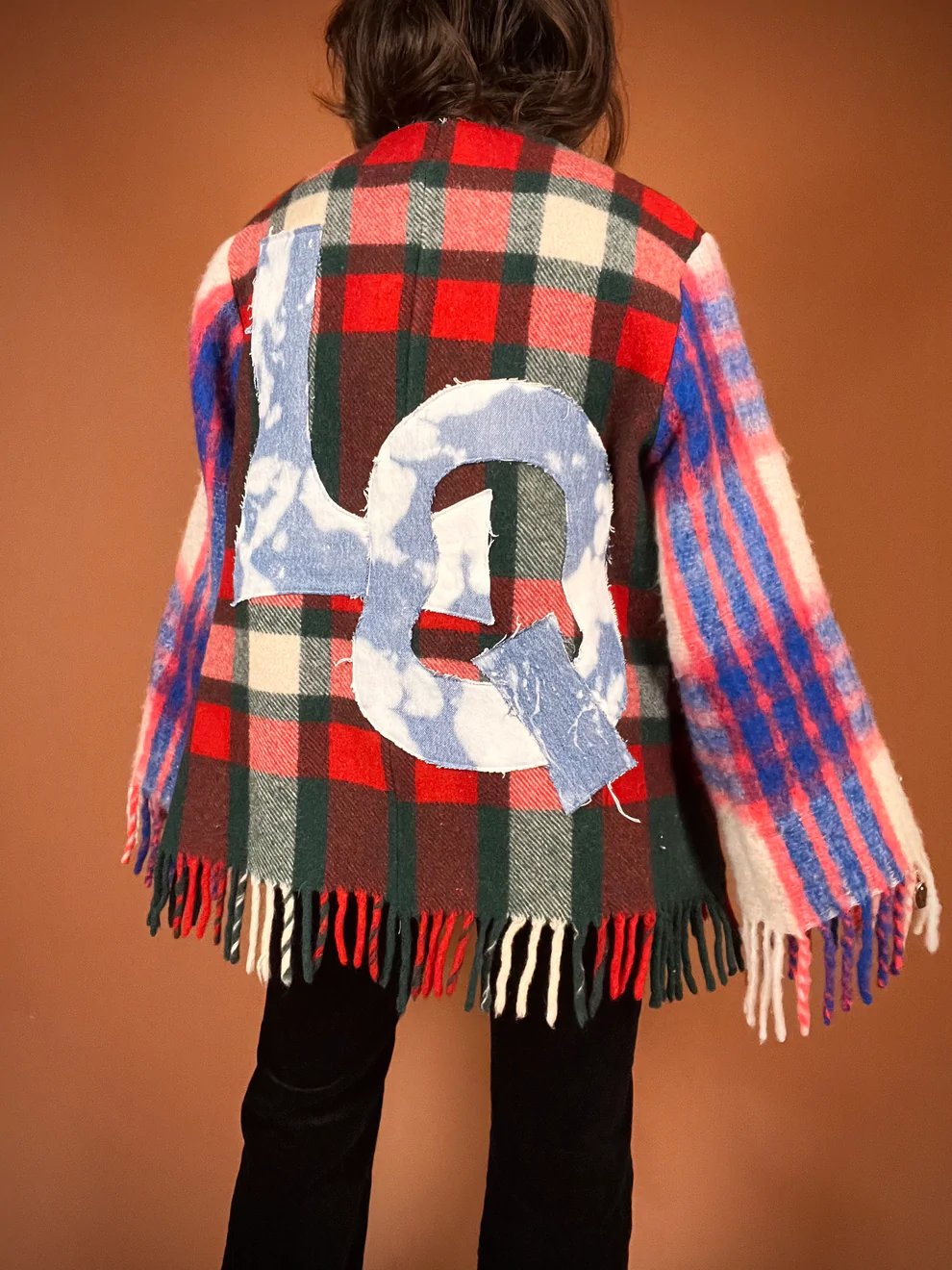 a young girl wearing a plaid jacket with the letter q on it.
