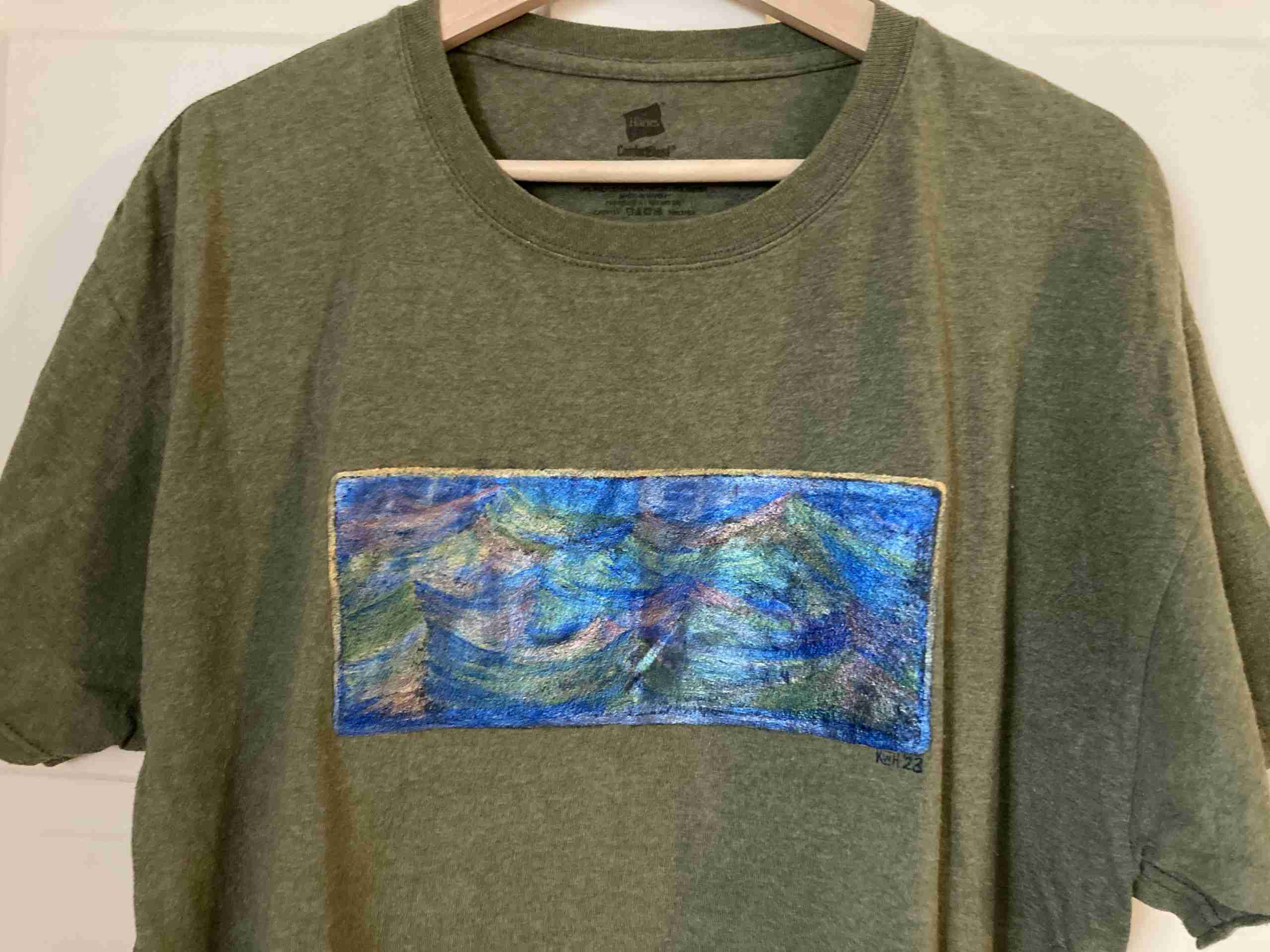 a green t - shirt with a painting on it.