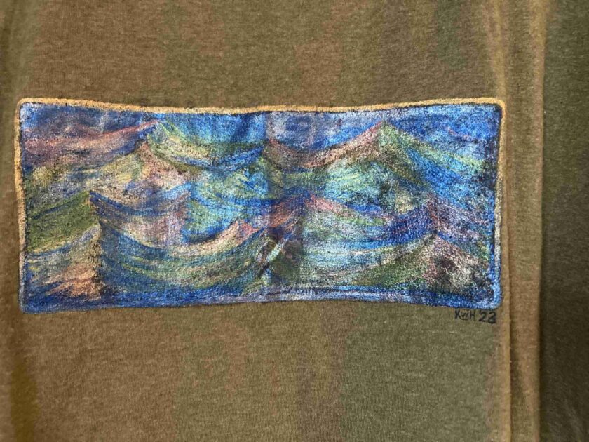 a close up of a shirt with a painting on it.