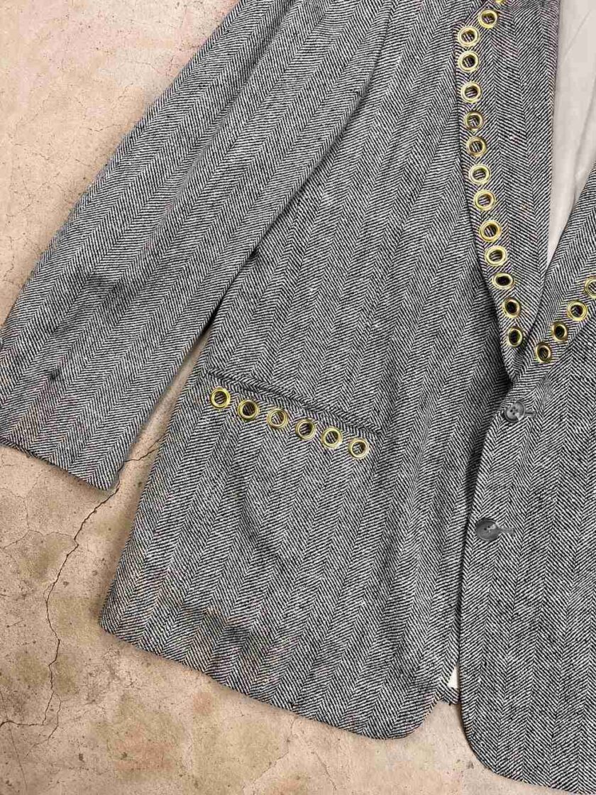 a gray jacket with gold buttons and a white shirt.