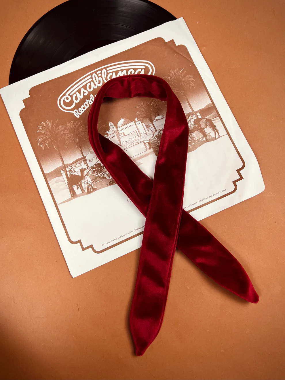 a red ribbon laying on top of a record.