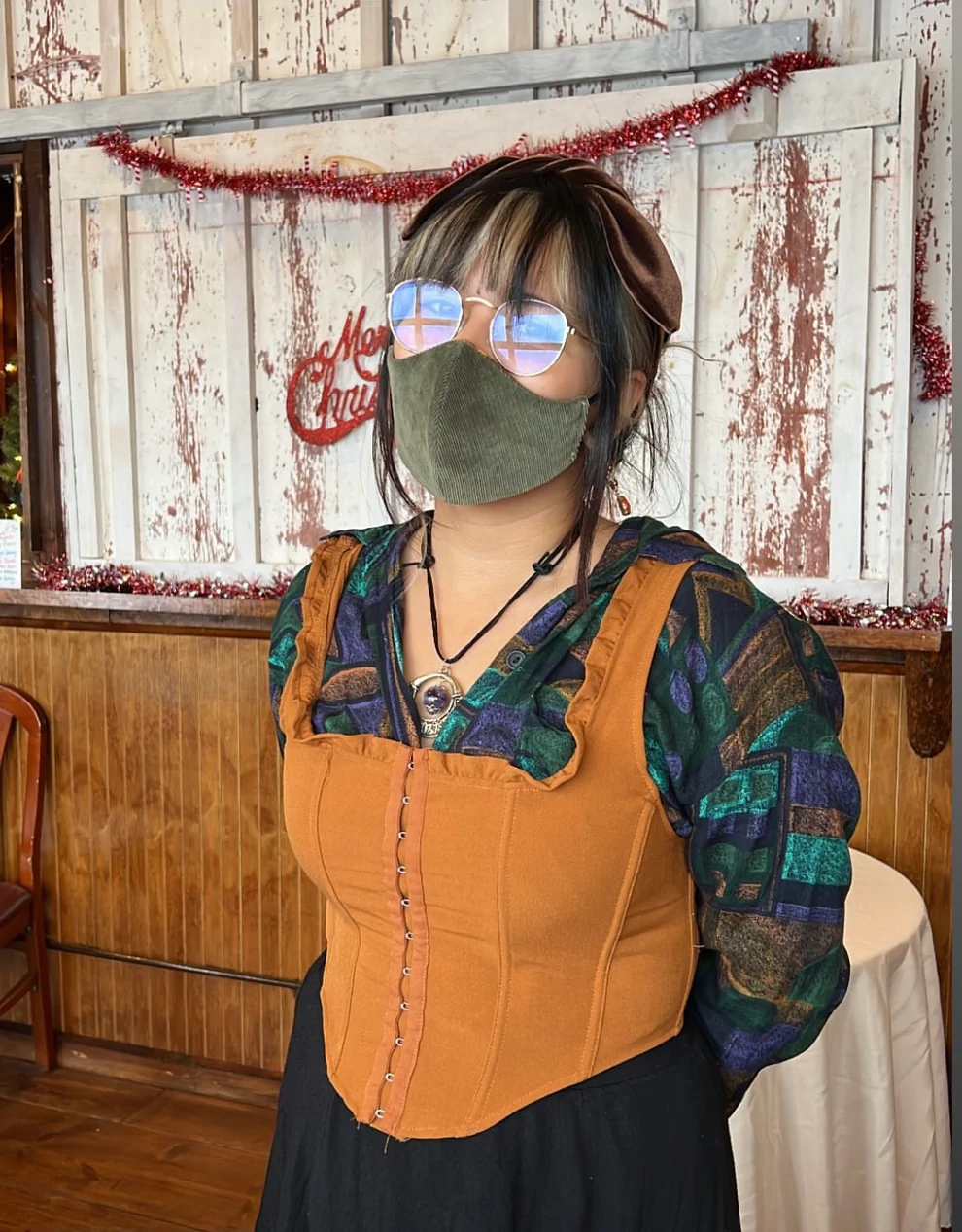 a woman wearing a green mask and an orange top.