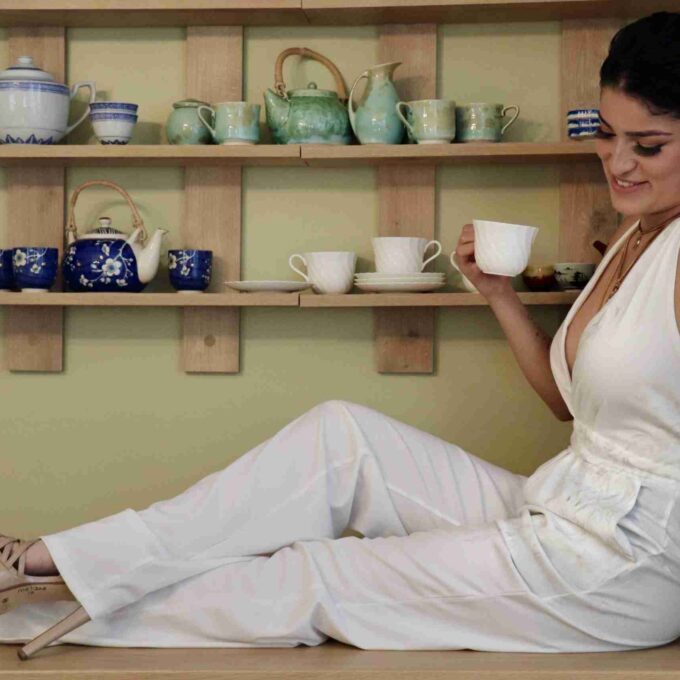 a woman sitting on a counter with a cup of coffee.