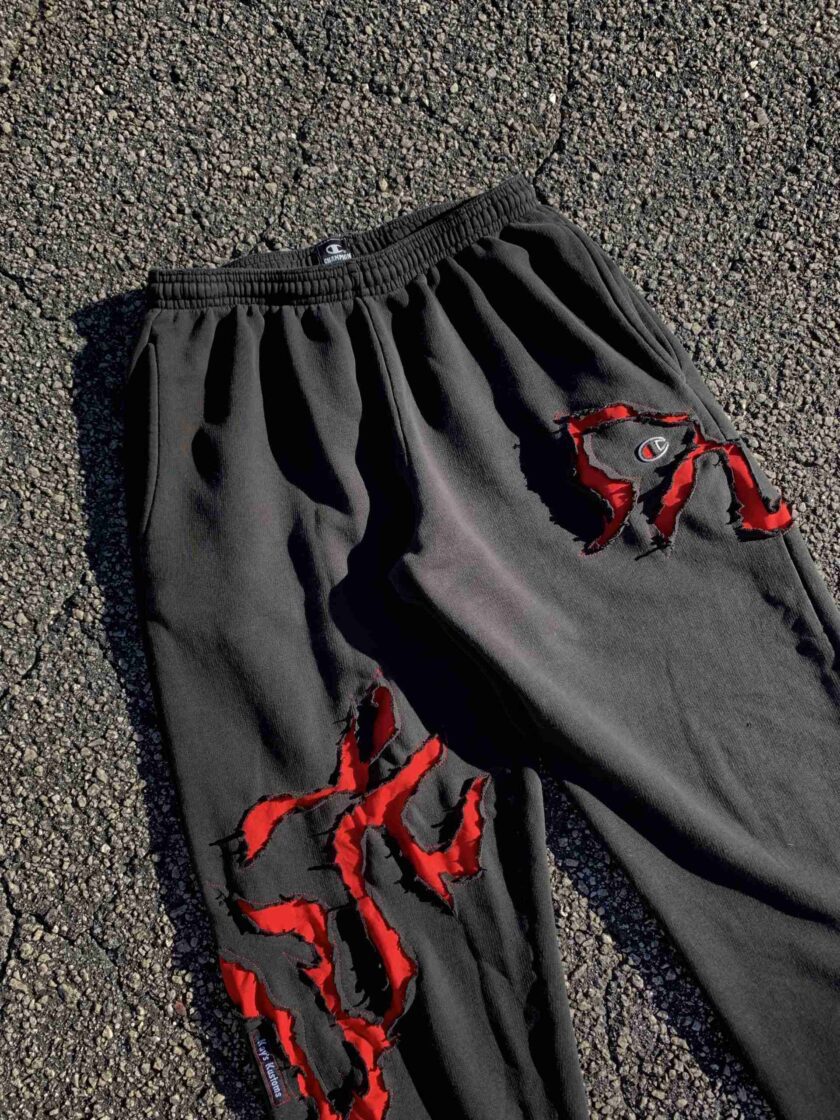 a pair of black sweatpants with red paint on them.