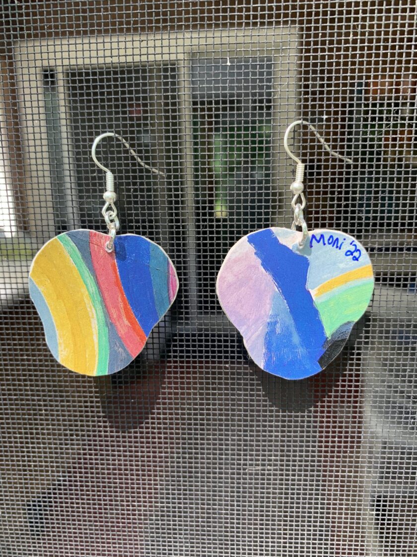 a pair of earrings with a painted fish on them.