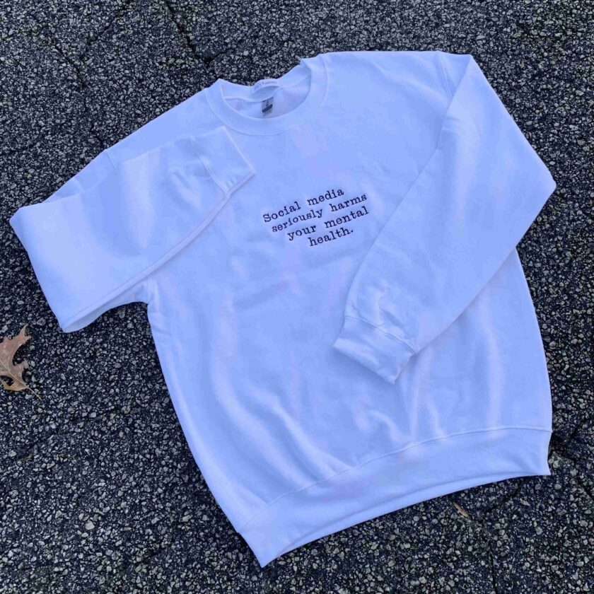 a white sweatshirt with writing on it laying on the ground.