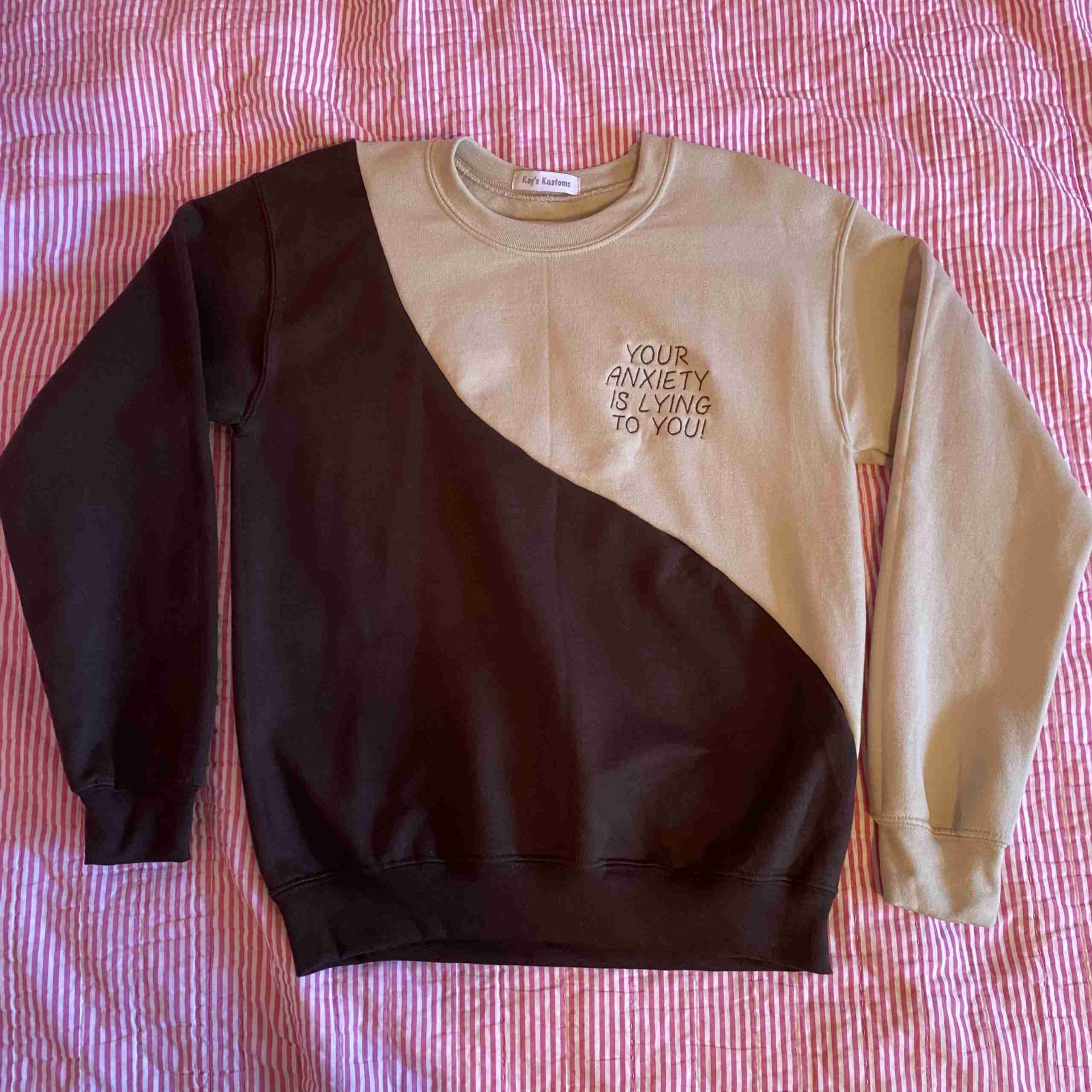 a black and tan sweatshirt with a white and brown design on it.