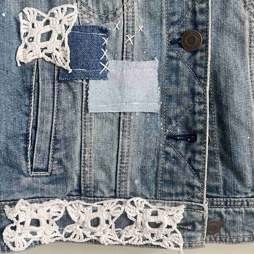 a jean jacket with a patchwork design on the back of it.