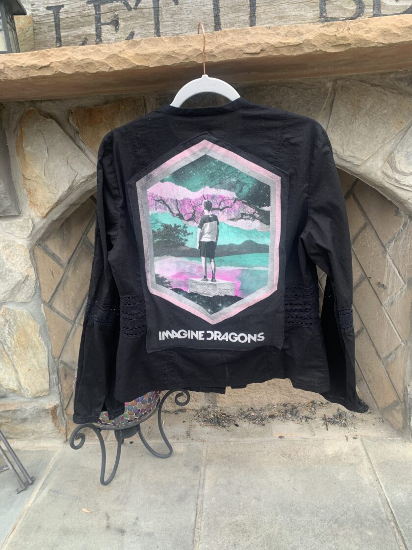 a black jacket with a picture of a person standing in front of a stone fireplace.
