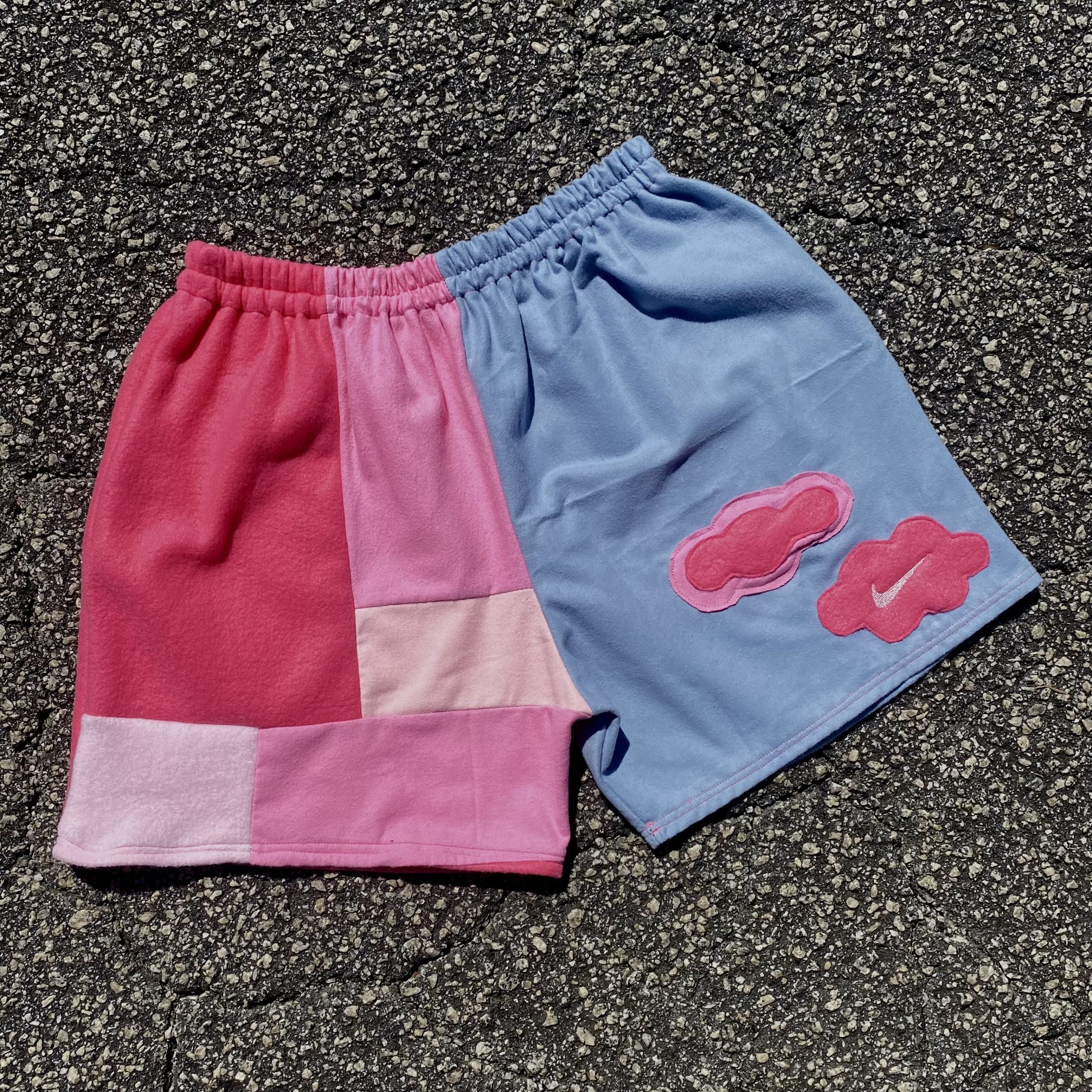 Two Cotton Candy Nike Shorts with pink and blue patches on them.