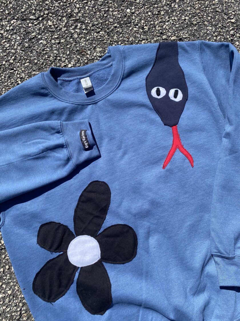 a blue shirt with a black flower on it.