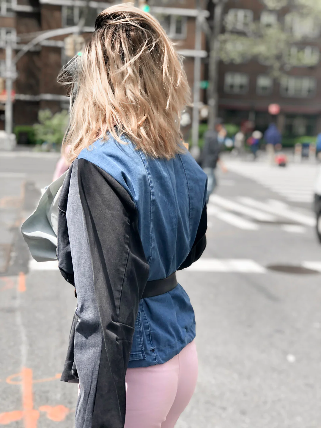 A woman in tights and an Up-Cycled Denim Jacket crossing the street.