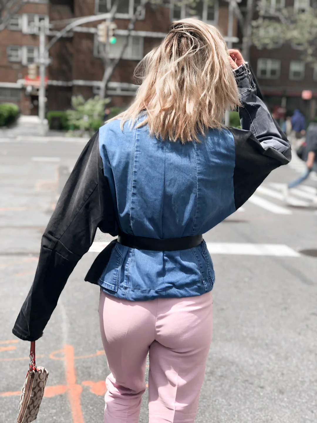 A woman walking down a street wearing an Up-Cycled Denim Jacket.