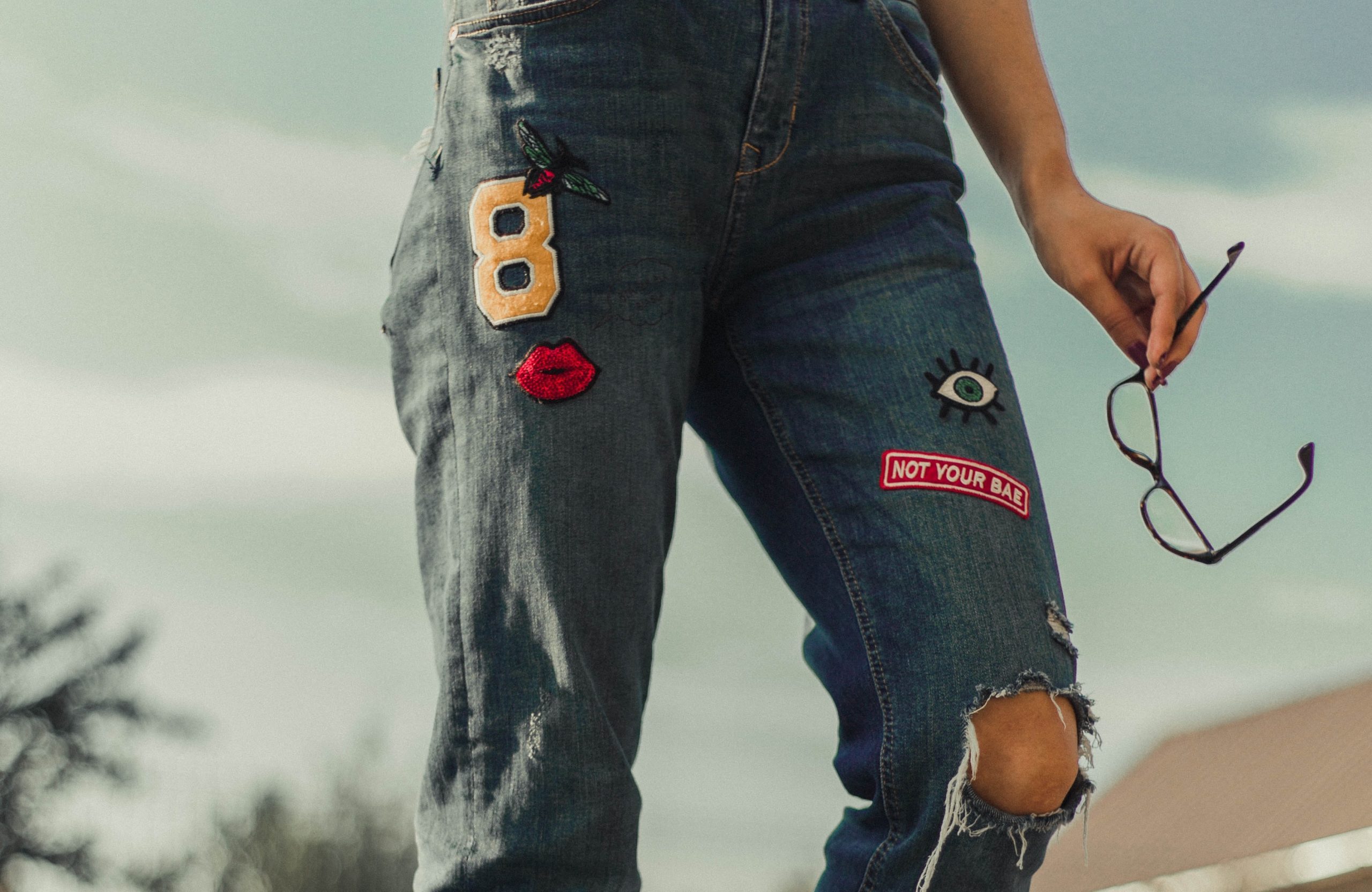 a person wearing a pair of jeans with patches on them.