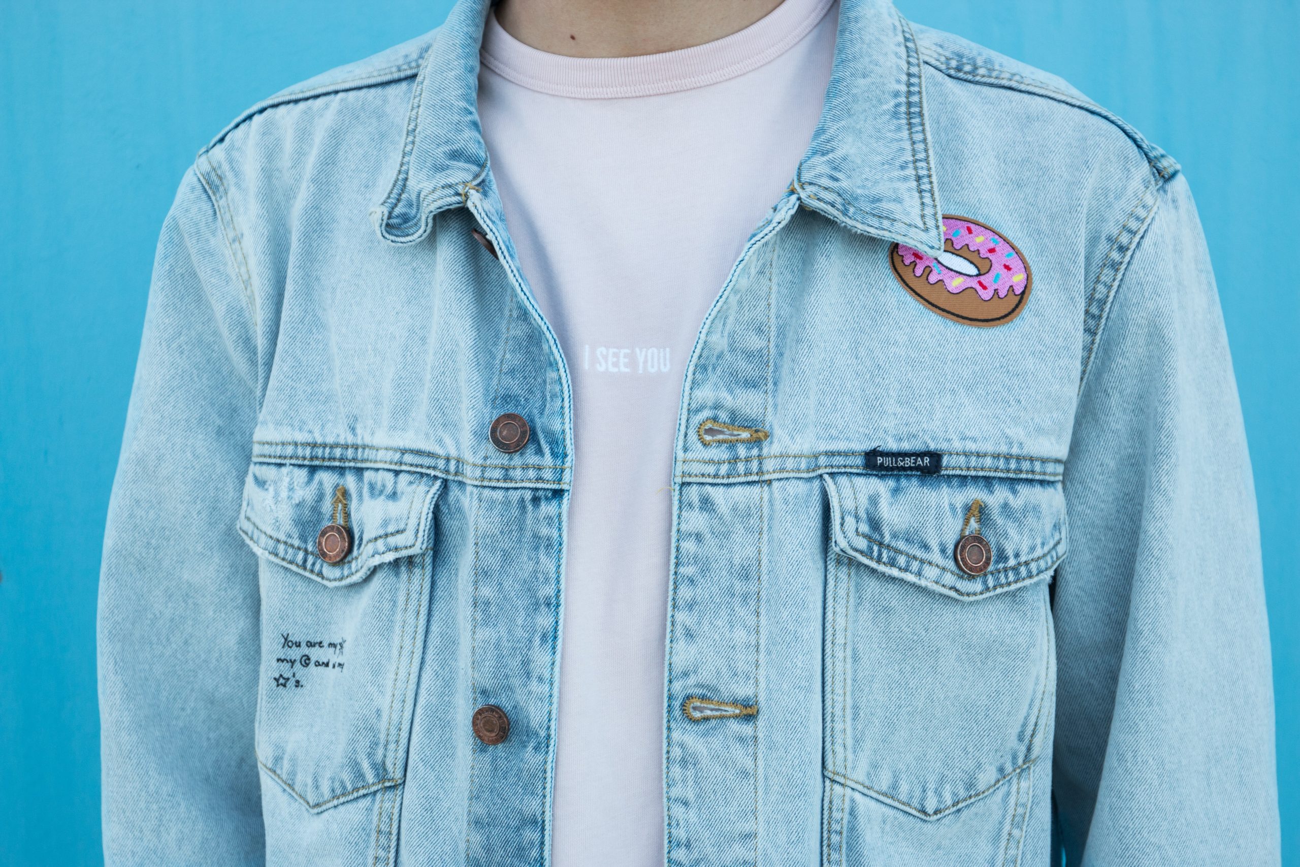 a person wearing a denim jacket with a donut on it.