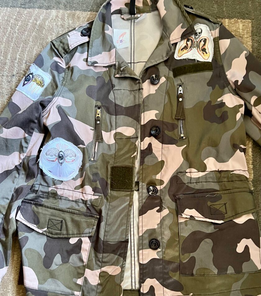 A PATCHED UP PINK CAMO JACKET with patches on the chest.