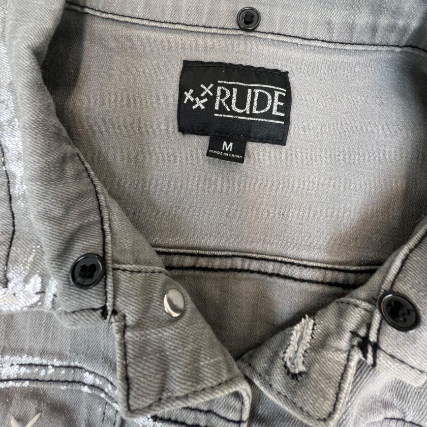 A close up of a label on a RUDE eye gray denim jacket.