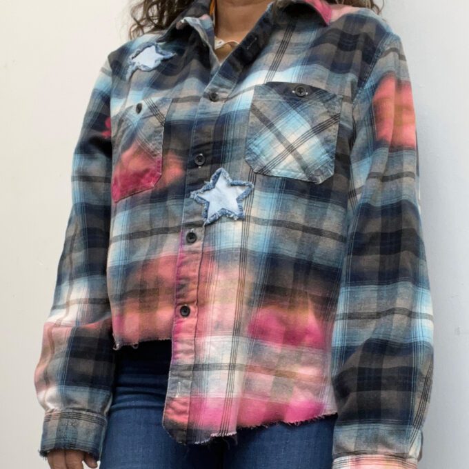 A woman standing against a wall wearing a Sunflower Bleached Flannel shirt.