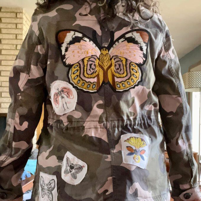 A person wearing a patched up pink camo jacket.
