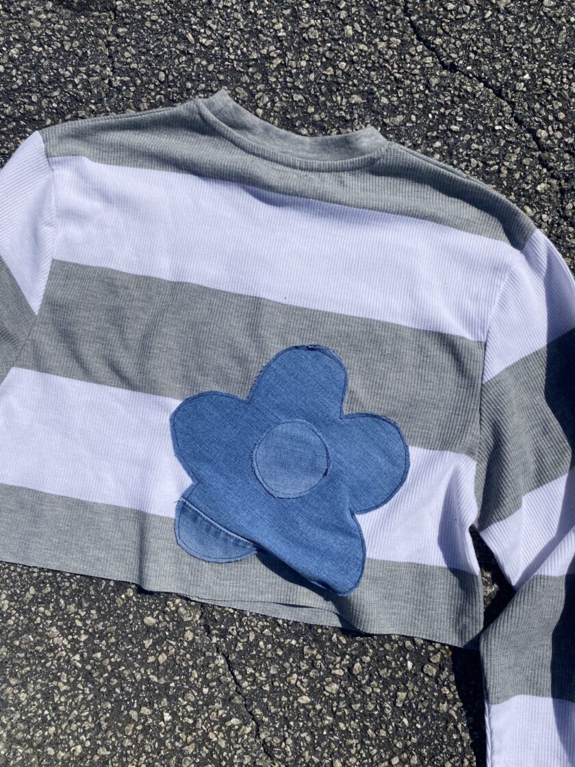 a striped shirt with a blue flower on it.