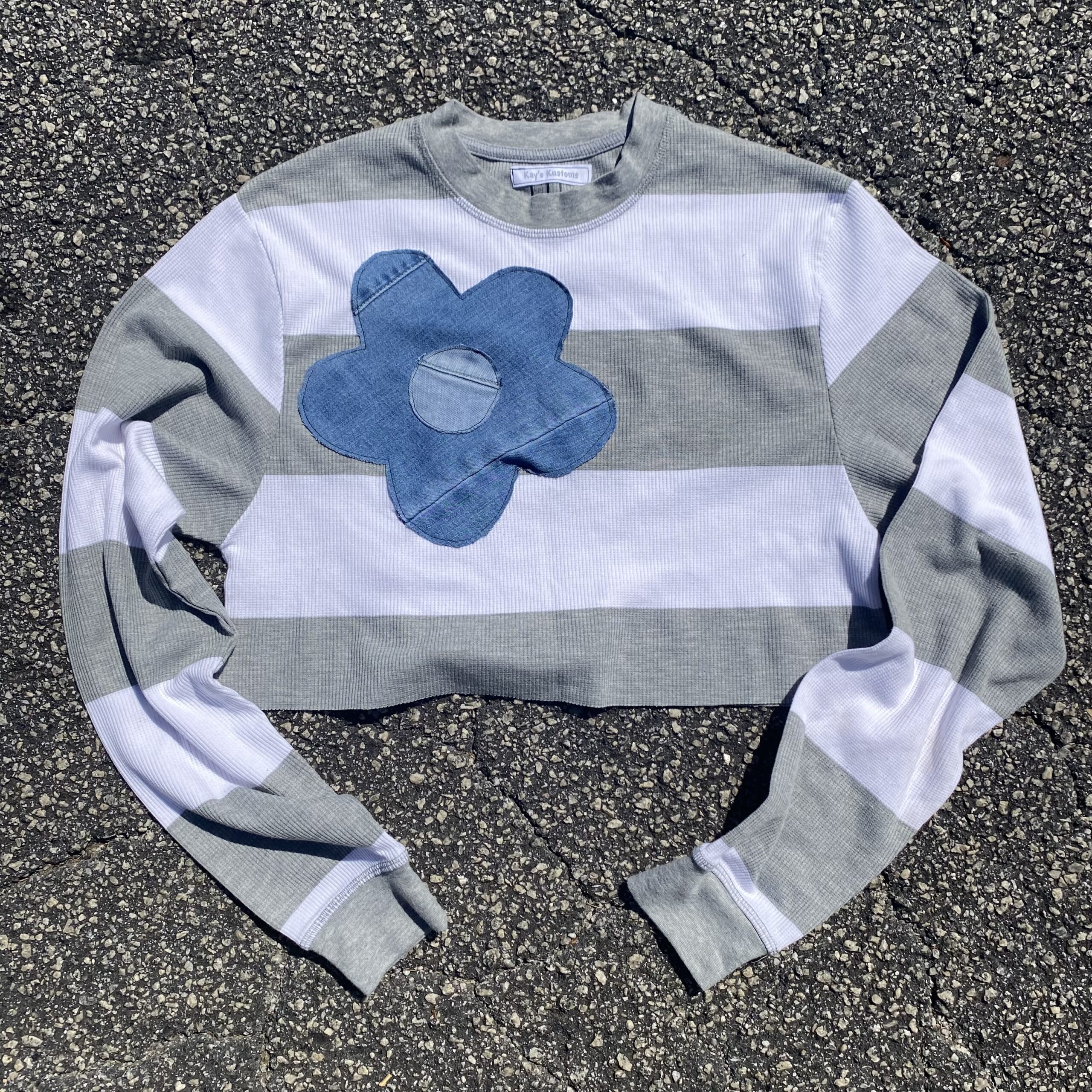 a striped shirt with a blue flower on it.