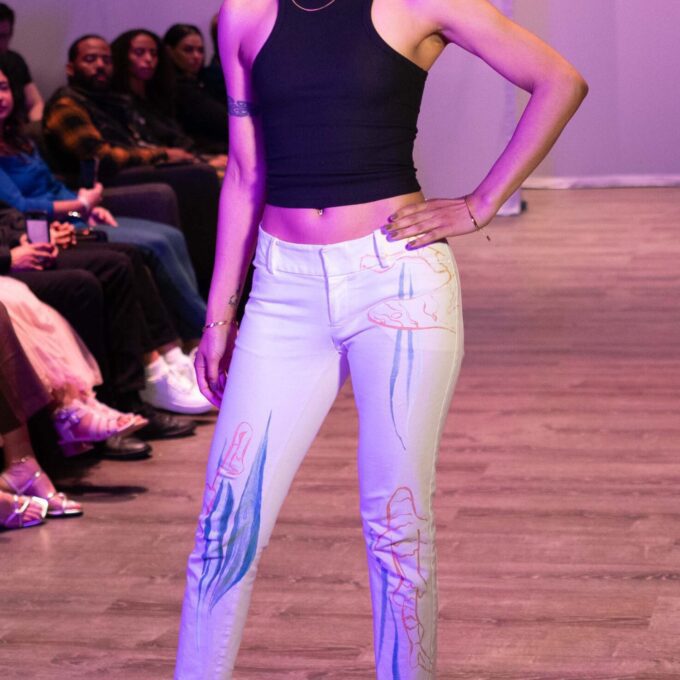 a woman standing on a runway with her hands on her hips.
