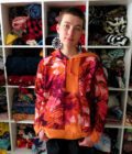 A woman standing in front of a closet full of Patchwork Marbled Orange Hoodies (Small).
