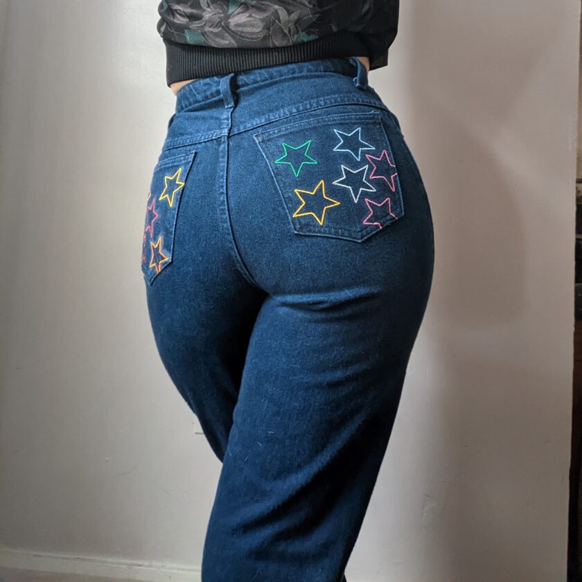 A woman in Reworked Embroidered Rainbow Star Pocket Jeans.