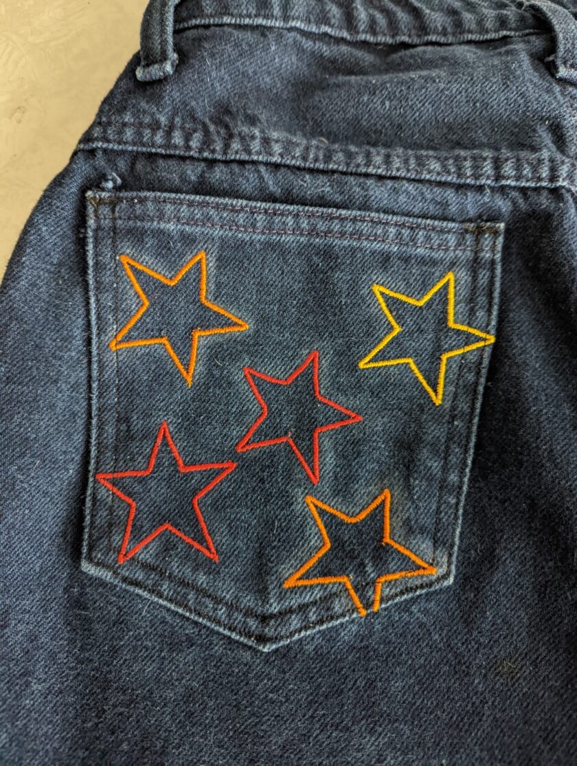 A pair of Reworked Embroidered Rainbow Star Pocket Jeans.