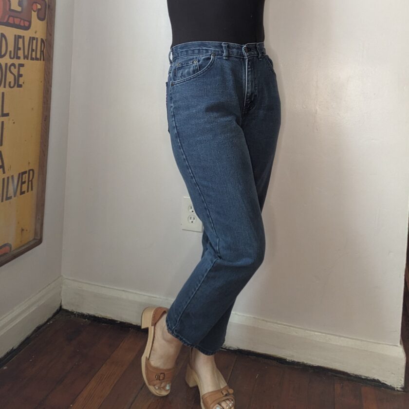 a woman leaning against a wall with her hand on her head while wearing Rainbow Star Jeans.