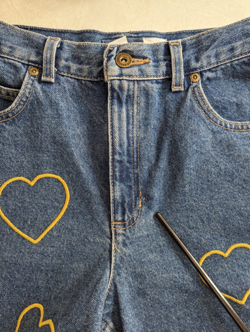 a pair of Embroidered Heart Shorts with a pair of scissors sticking out of the back.