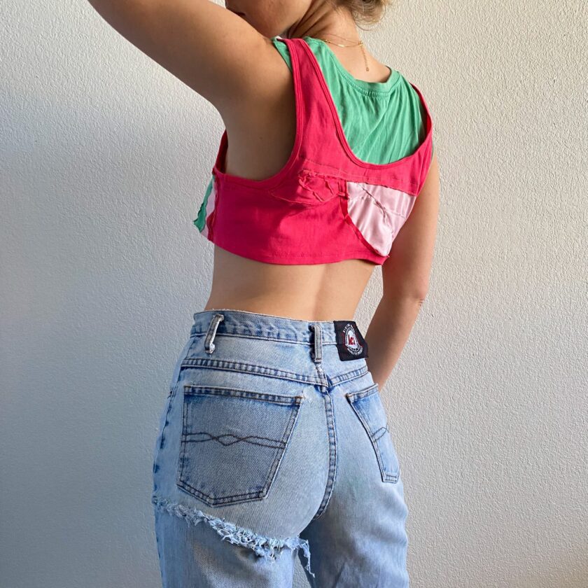 A woman wearing a 1of1 pink and mint tee tank top and jeans.