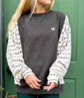 A woman standing in front of a green door wearing a Reworked Vintage Champion Neutral Crewneck.