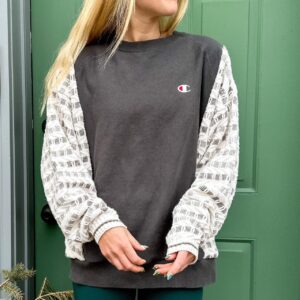 A woman standing in front of a green door wearing a Reworked Vintage Champion Neutral Crewneck.