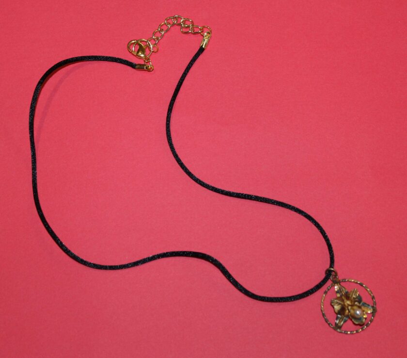 black silk cord necklace with antique weathered orchid pendant on red background