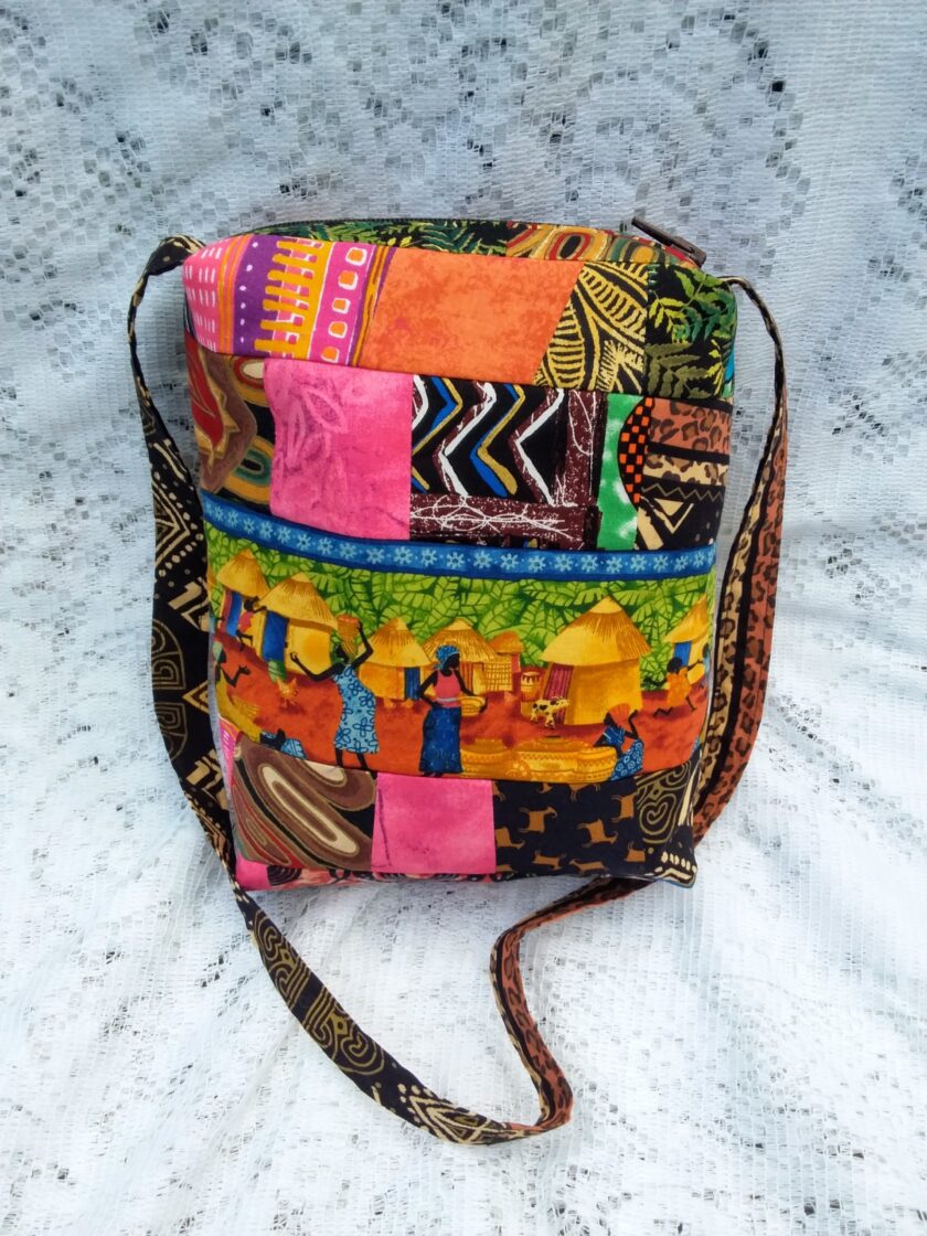 This lovingly handcrafted handbag evokes the feel of an African Village as women and children dance their way through a field of sunflowers and around the circumference of the bag.