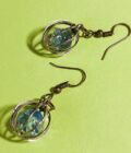 view of two pierced earrings with "caged" free floating blue bead in each