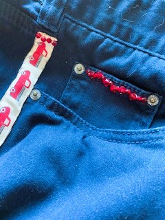 Close up of read beading and trip on denim shorts