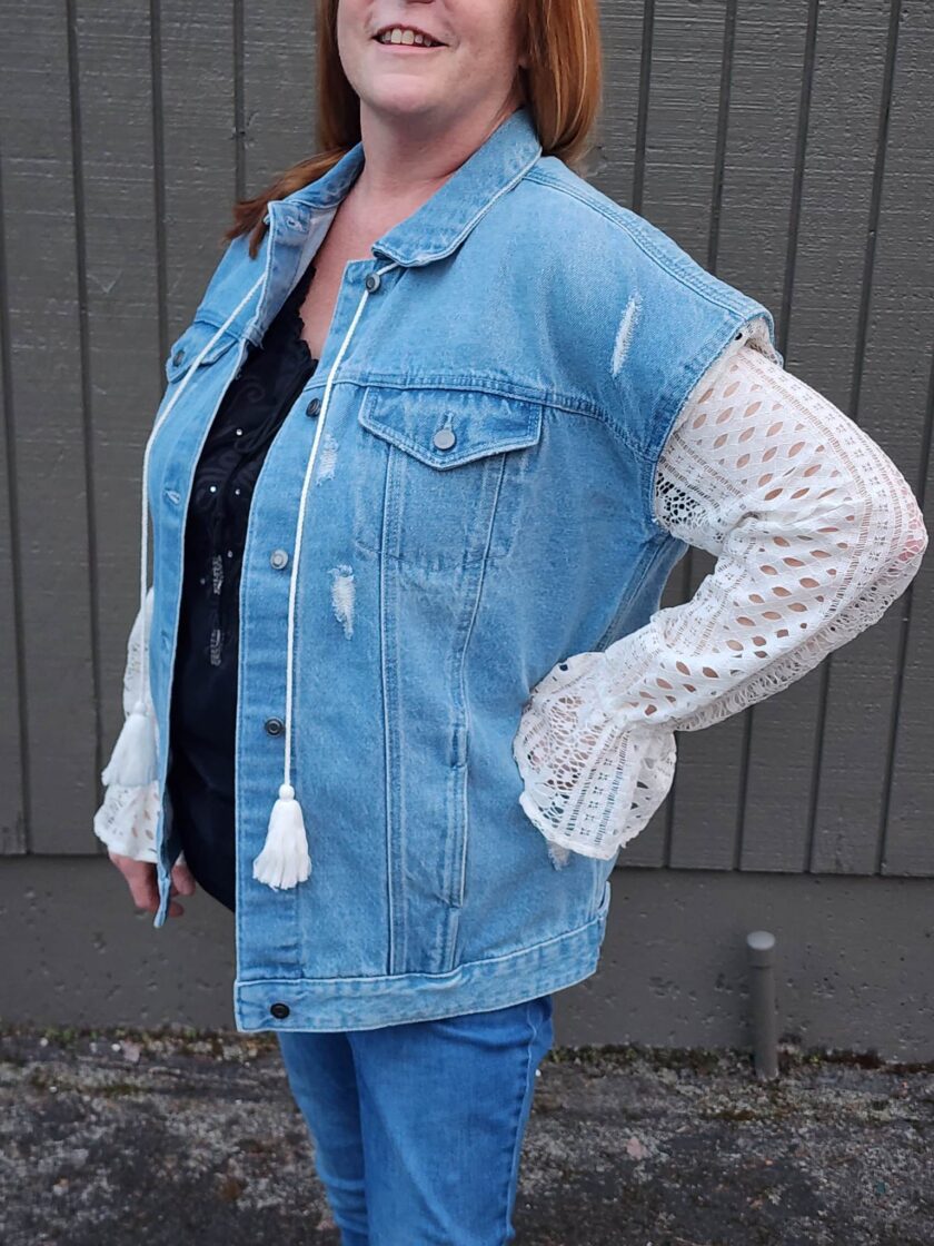 A woman with red hair wearing a Take Me To The Ocean upcycled denim & lace jacket.