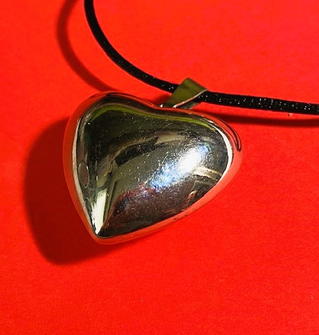 Large Silvertone heart pendant on a black silk cord on model
