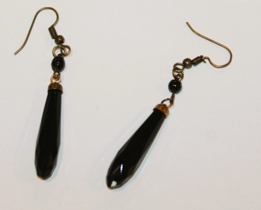 View of two antique jet earrings lying on white back ground