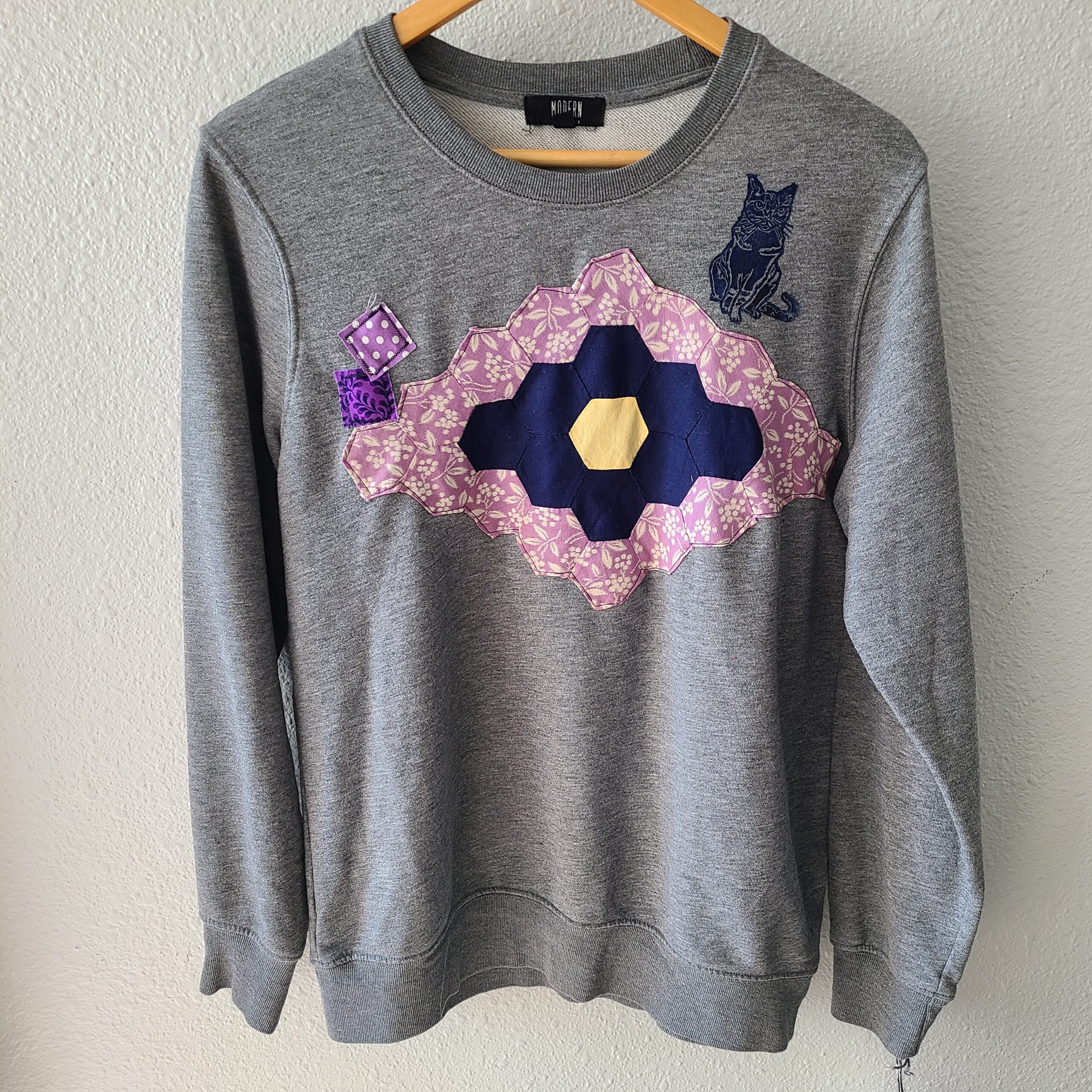 a gray sweater with a pink and blue design on it.
